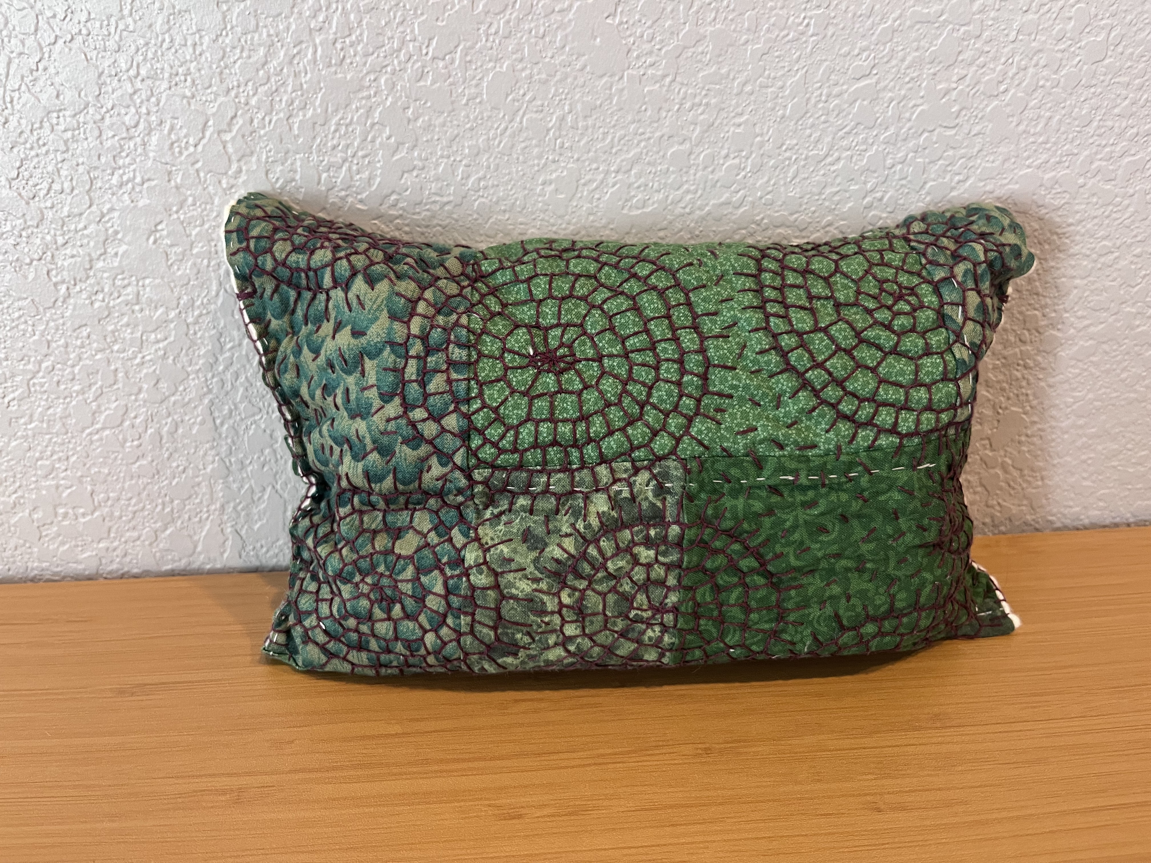 Photo of green patchwork envelope bag with decorative stitching covering the surface.