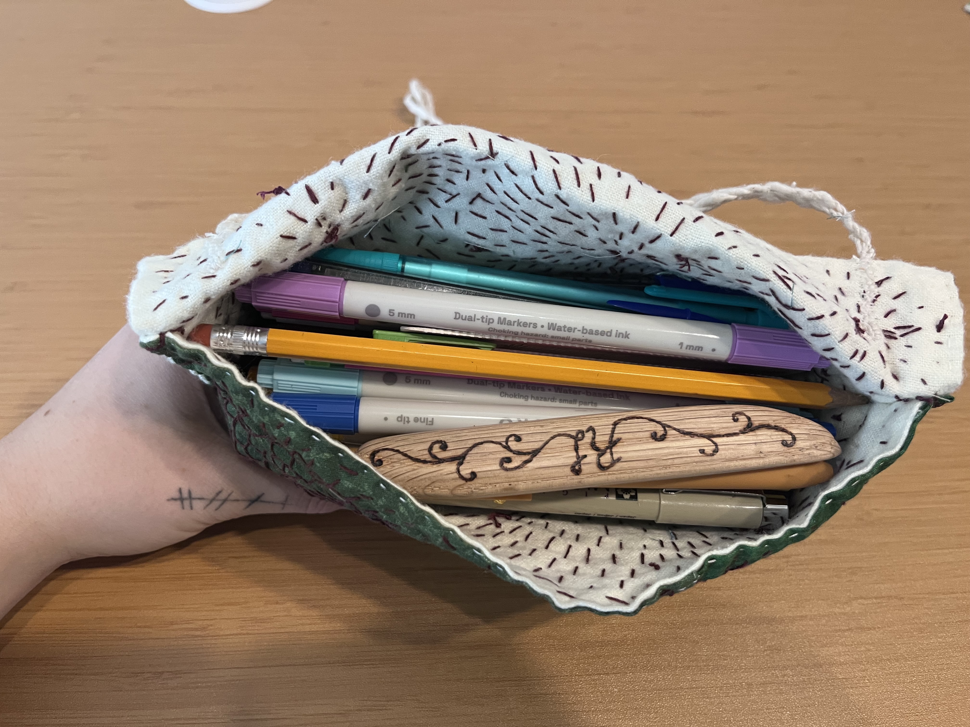 Photo of green patchwork envelope bag with decorative stitching covering the surface.